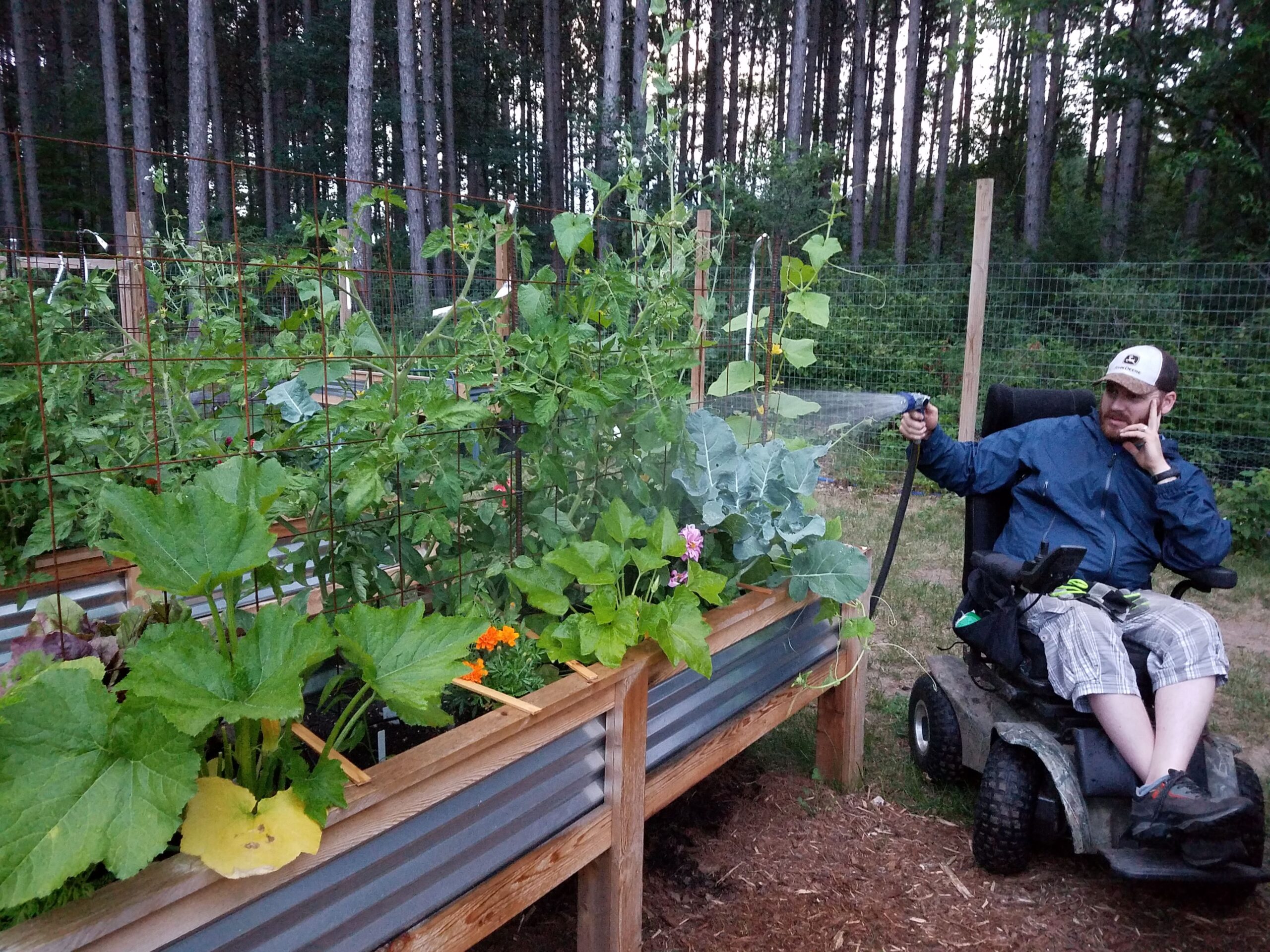 a man watering his raised garden bed